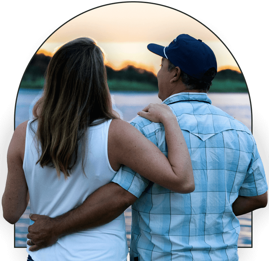 A couple with their backs to the camera looking at a lake